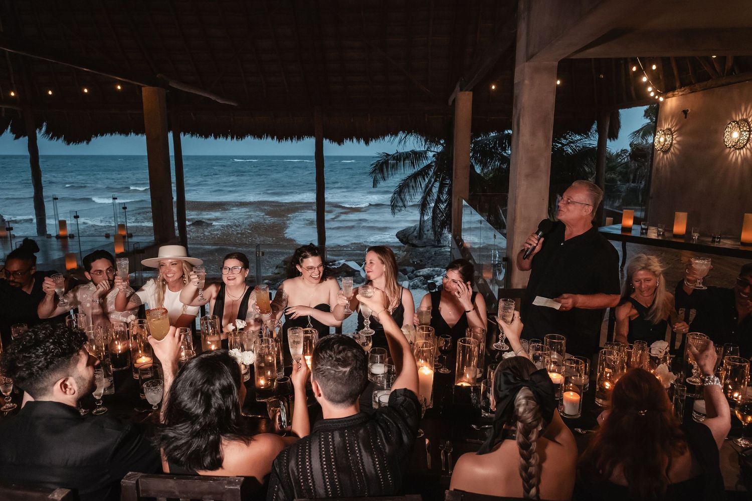 Guests raise their glasses in celebration at an elegant candlelit dinner reception.