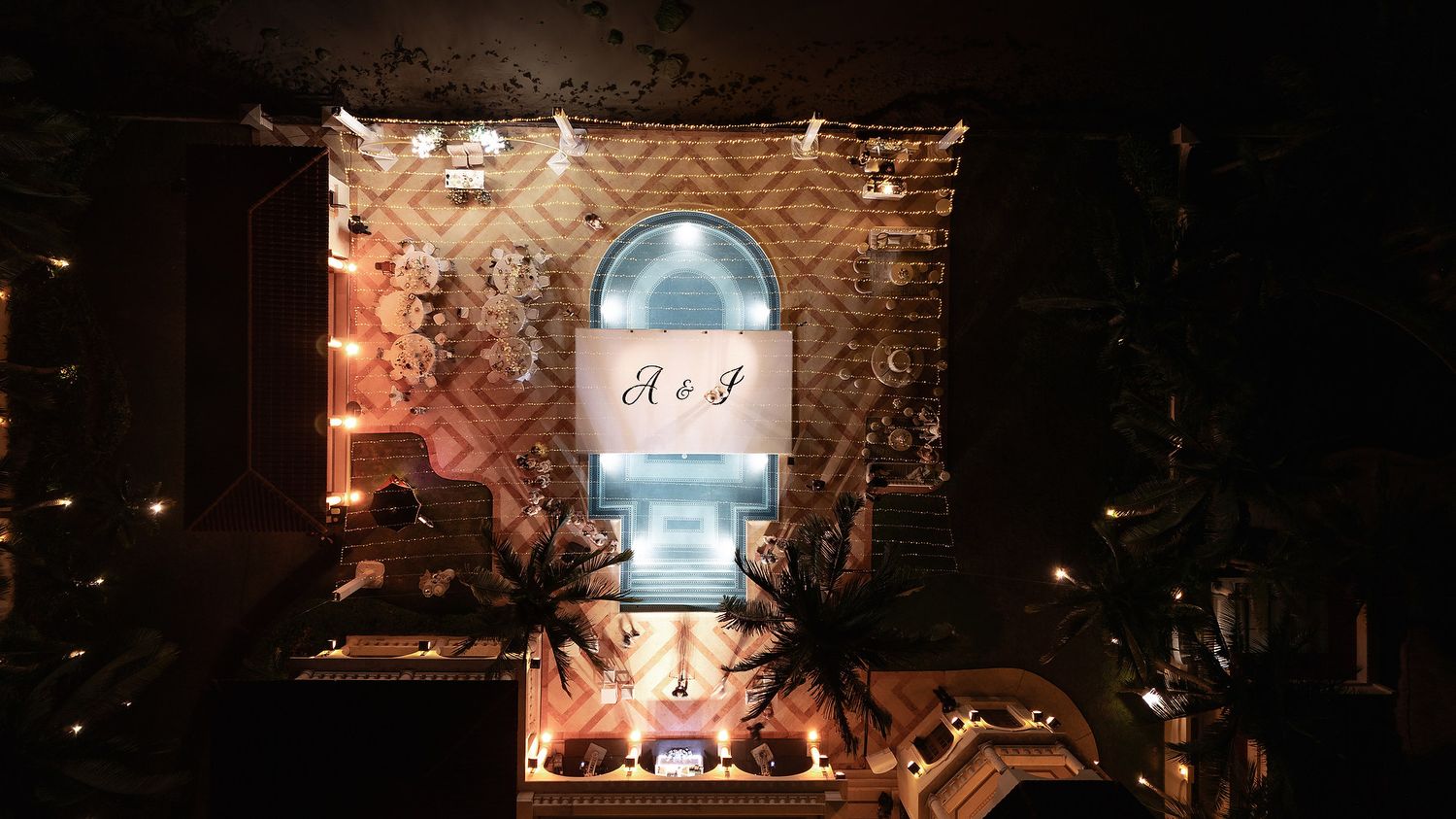 Wedding monogram projected onto building facade with dramatic lighting effects.