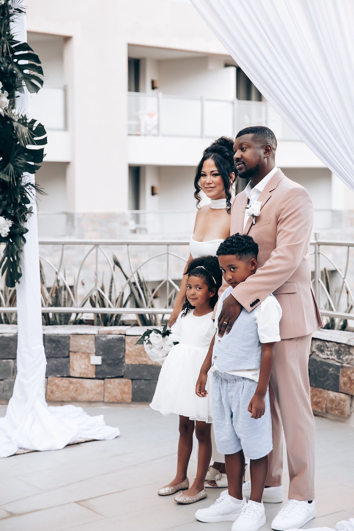 Family members share joyful moments together at an outdoor venue decorated with white drapes.