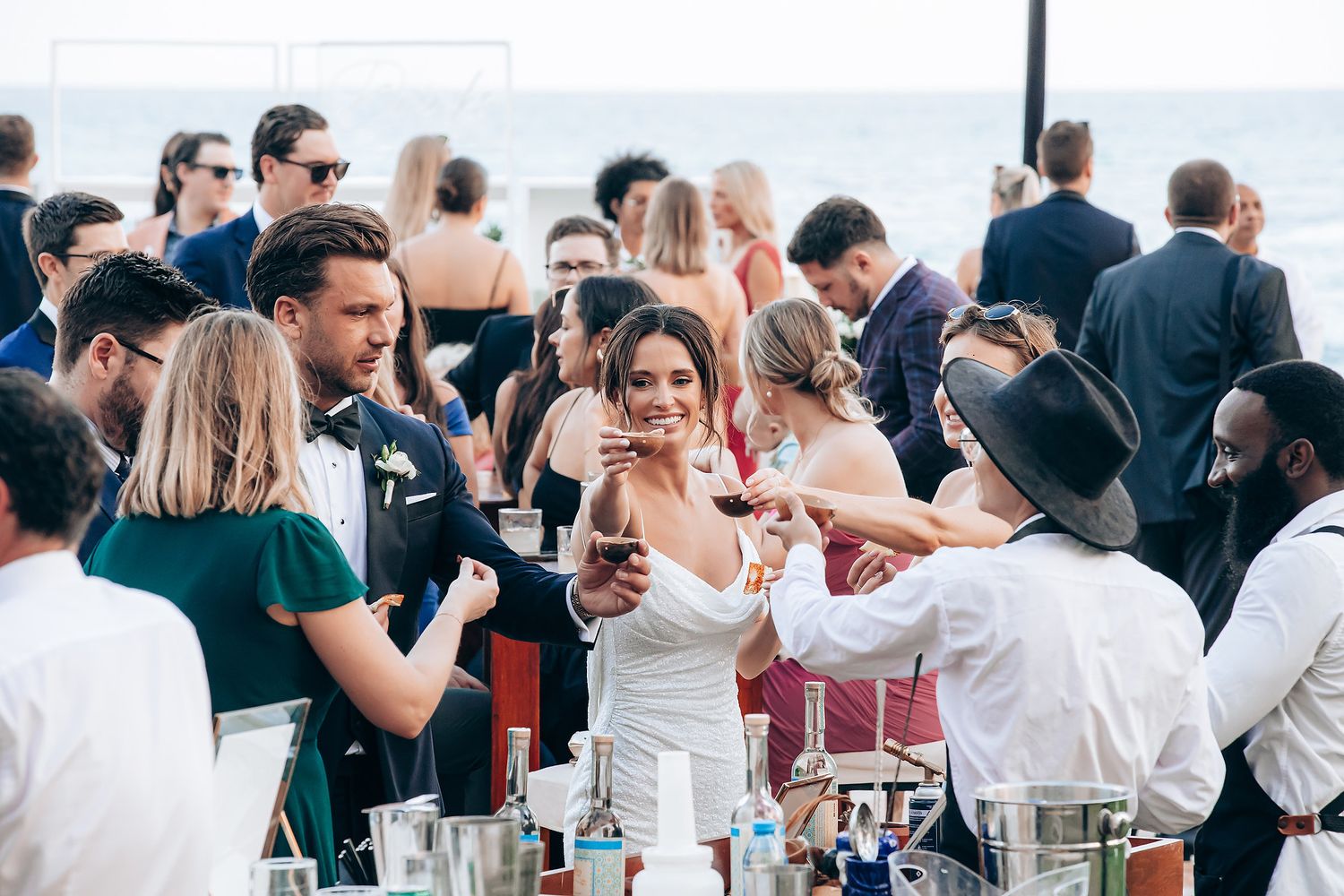 A large group of wedding guests enjoying a reception celebration with drinks and conversation.