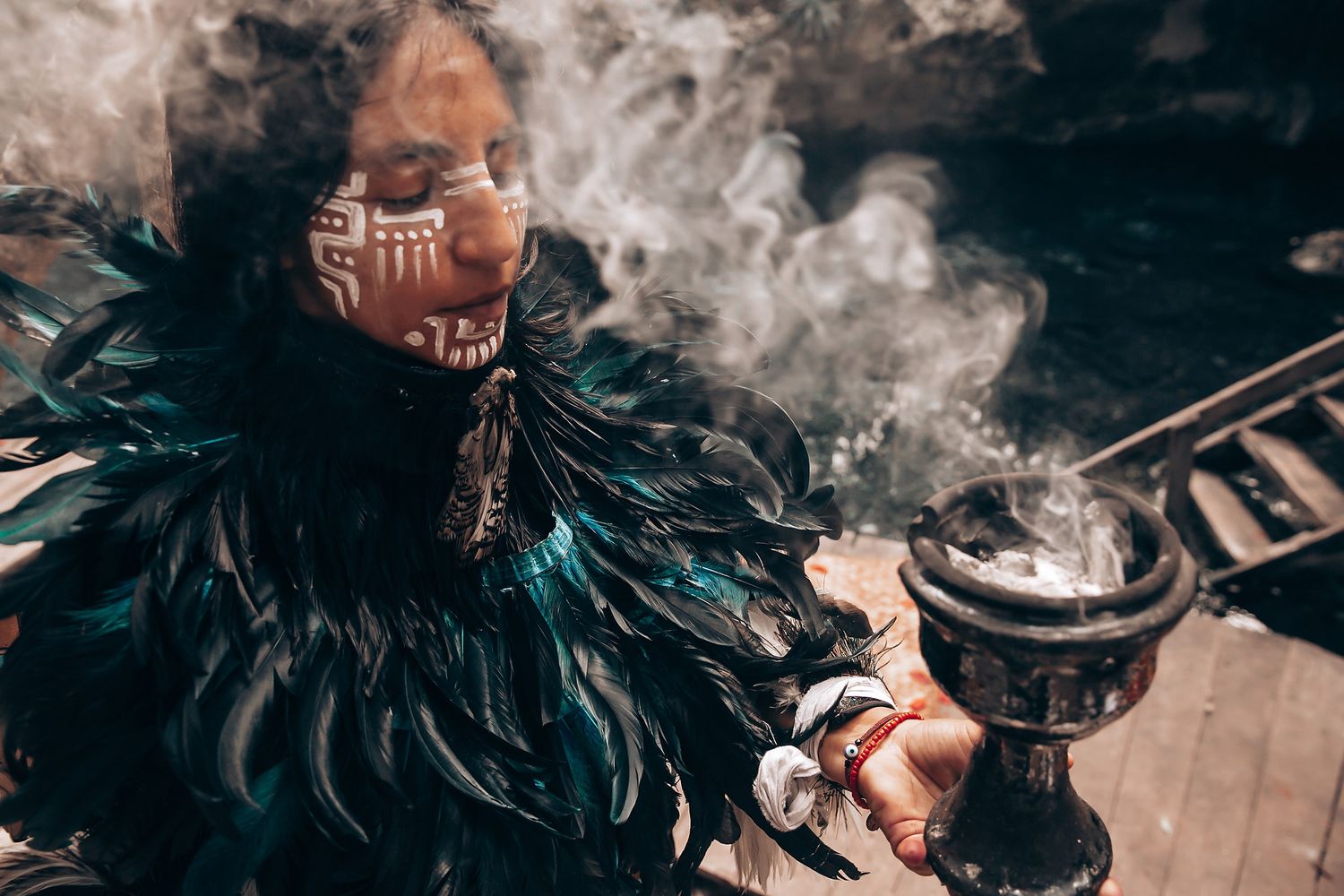 Smoke and feather decorations create an ethereal atmosphere at an outdoor wedding.