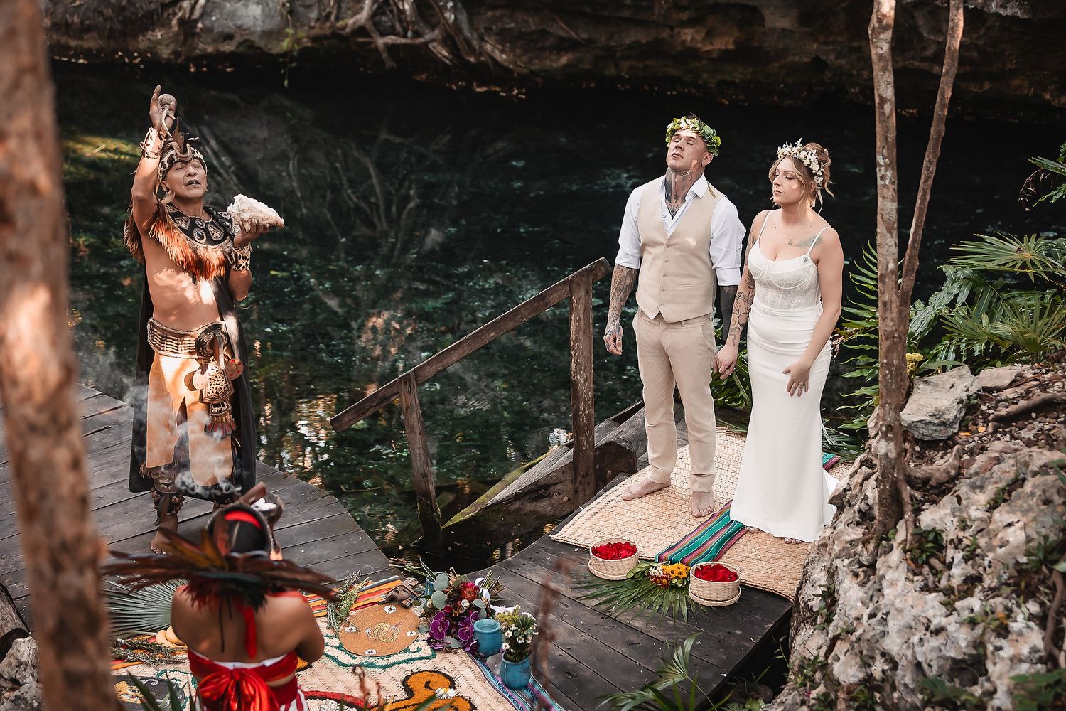 Couple exchanges vows in a cenote ceremony with a Mayan shaman officiating in Mexico.