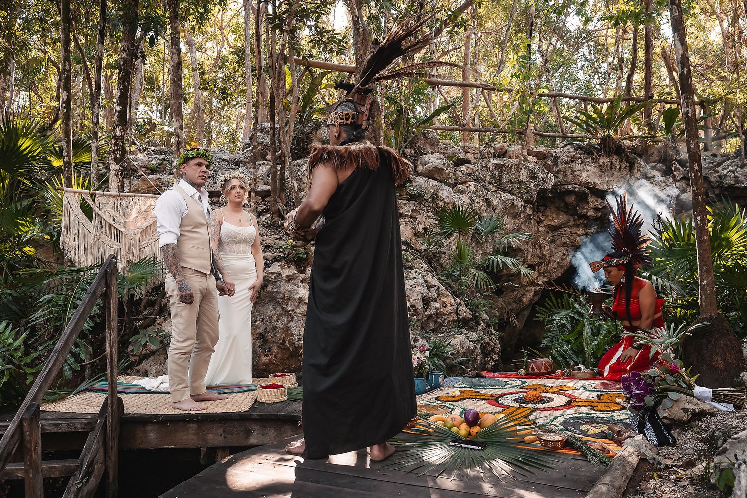 Couple exchanges vows in a Mayan ceremony in a lush jungle setting with a shaman and colorful altar.