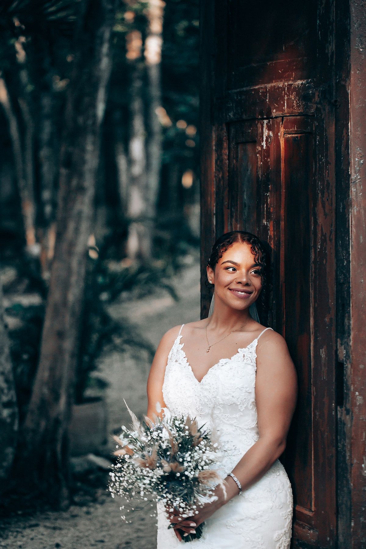 Elegant bridal portrait in a white lace dress against a rustic wooden backdrop.