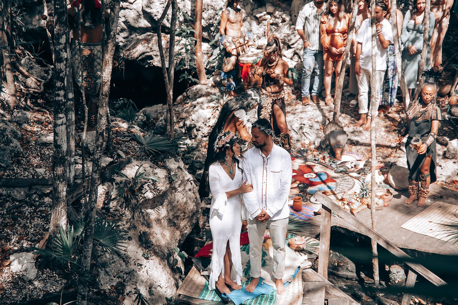 Attendees gather for a spiritual ceremony on an elevated wooden platform in a forest setting.
