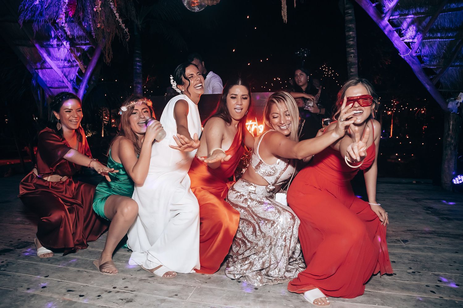 Nighttime celebration with purple and blue lighting illuminating dancing party guests.