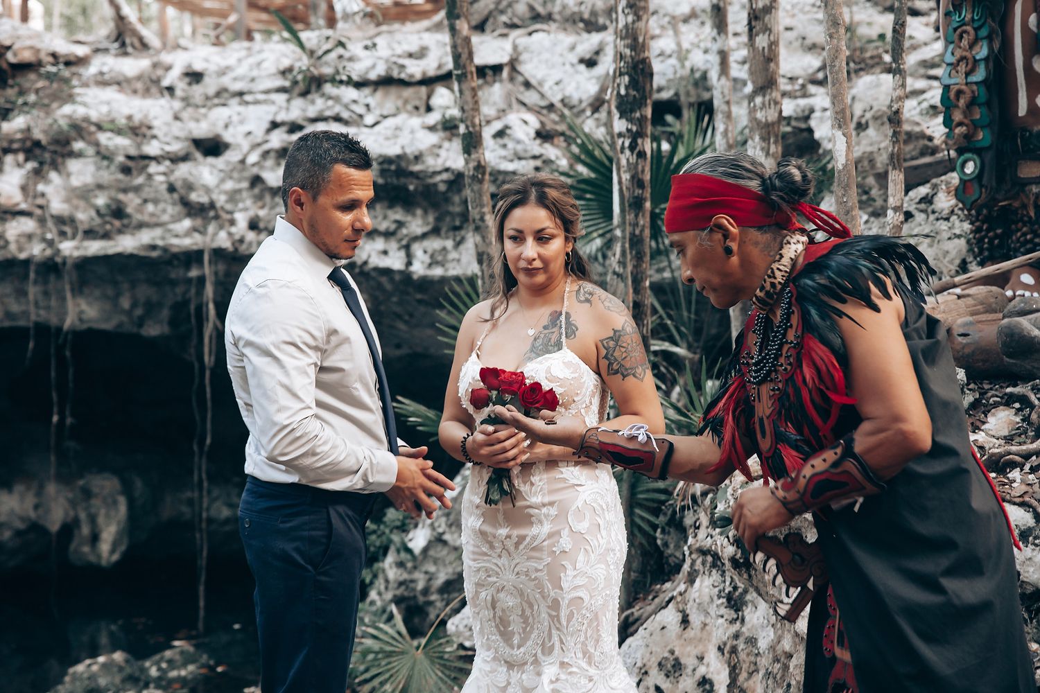 Outdoor wedding reception with guests mingling under string lights and tropical foliage.