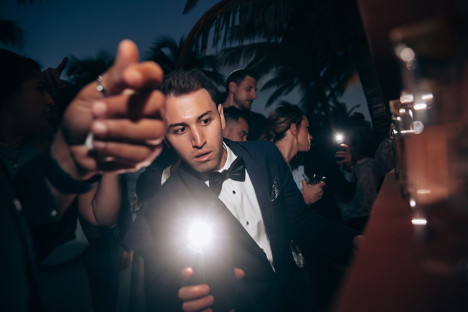 Atmospheric nighttime wedding reception with dramatic lighting and dancing.