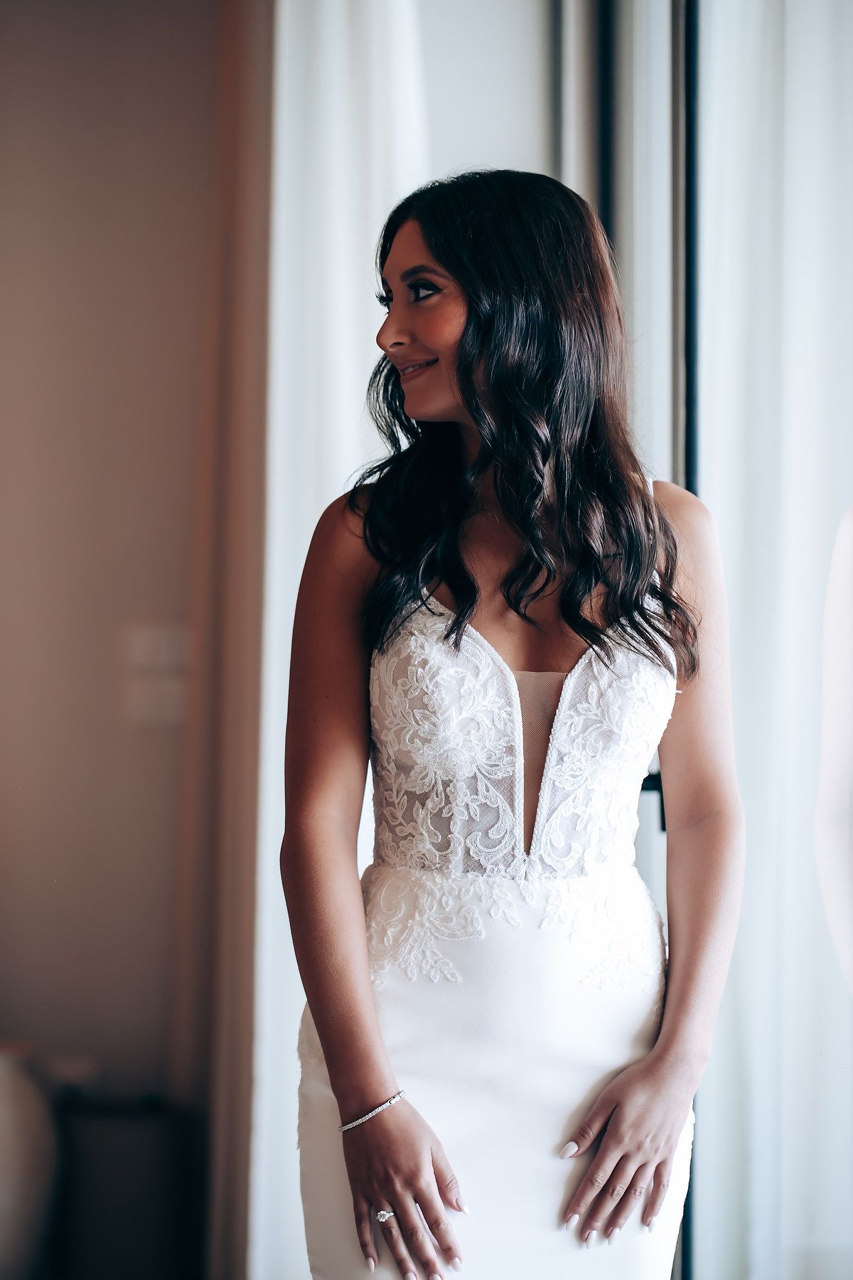 Bride in a beautiful white lace wedding dress with plunging neckline.