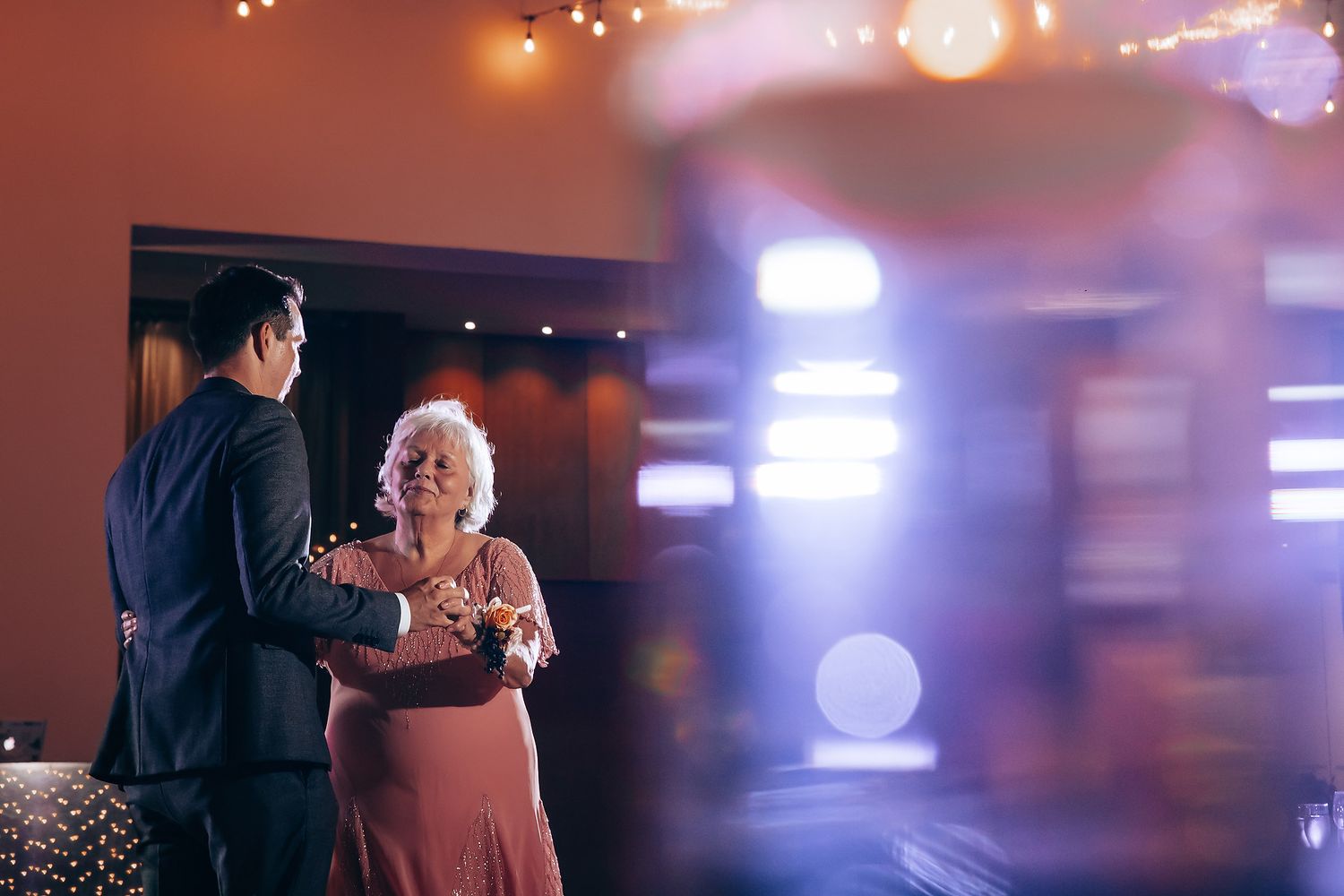 Wedding reception dance captured with atmospheric purple lighting and bokeh effects.