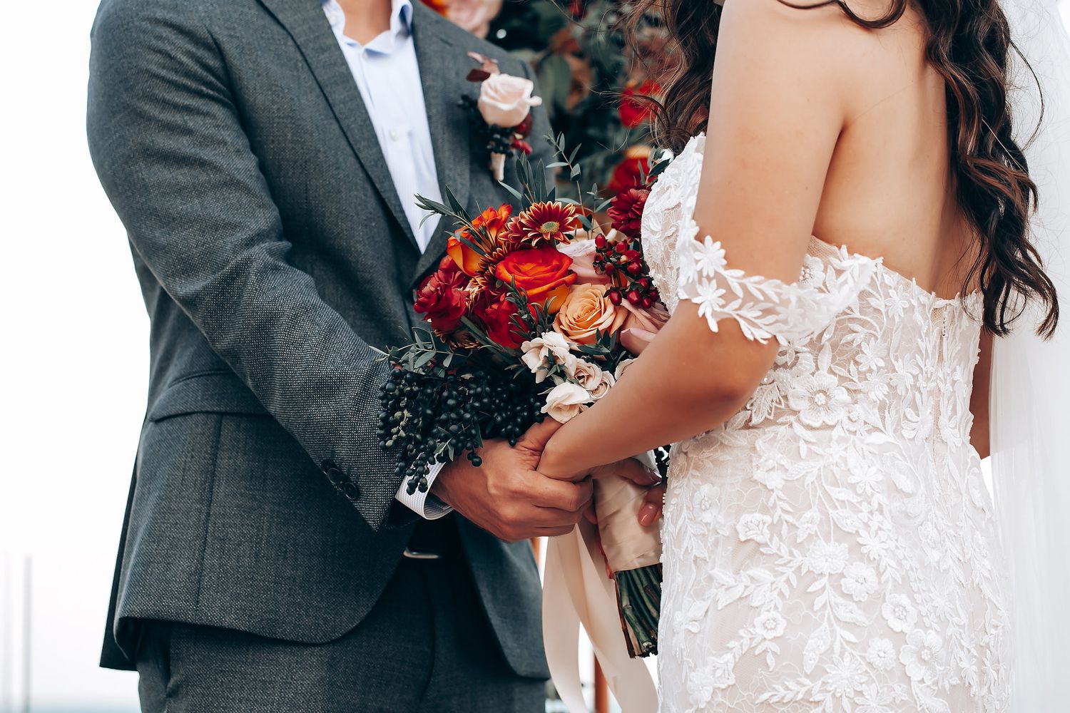 Close-up details of wedding attire showing lace dress and dark suit.
