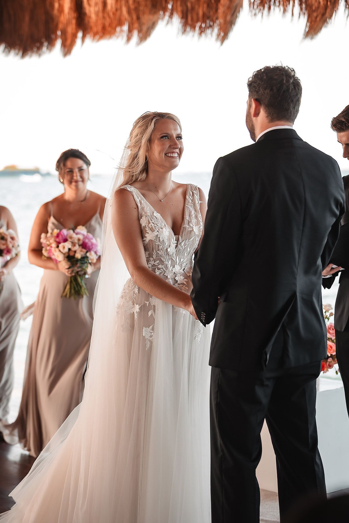 Intimate wedding ceremony moments under a thatched palapa roof by the ocean.