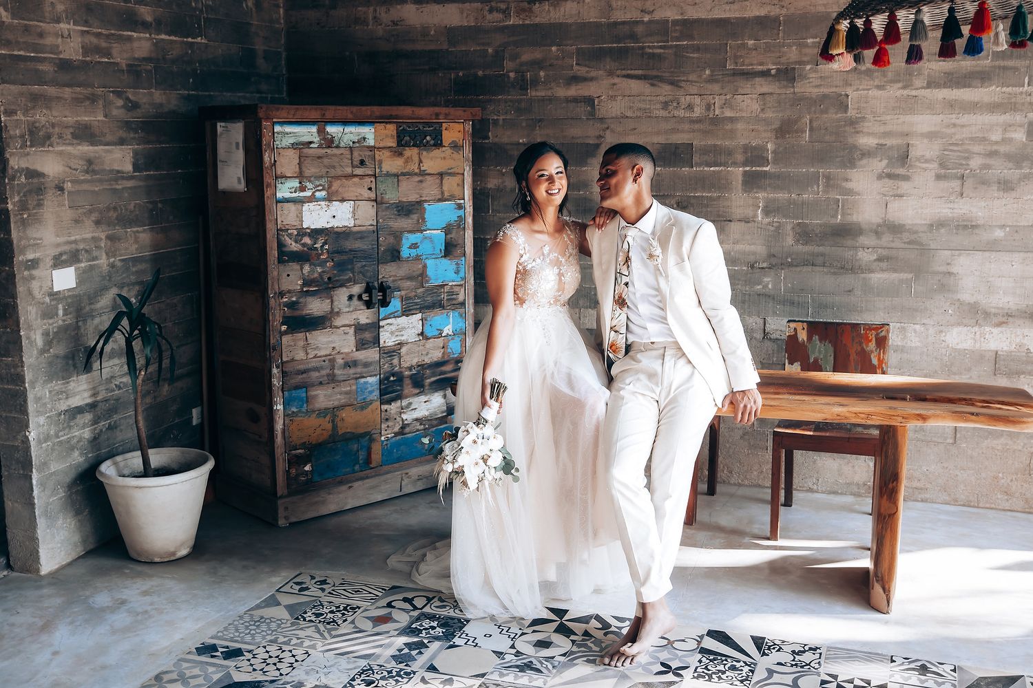Modern rustic wedding venue featuring wooden benches and decorative hanging tassels.