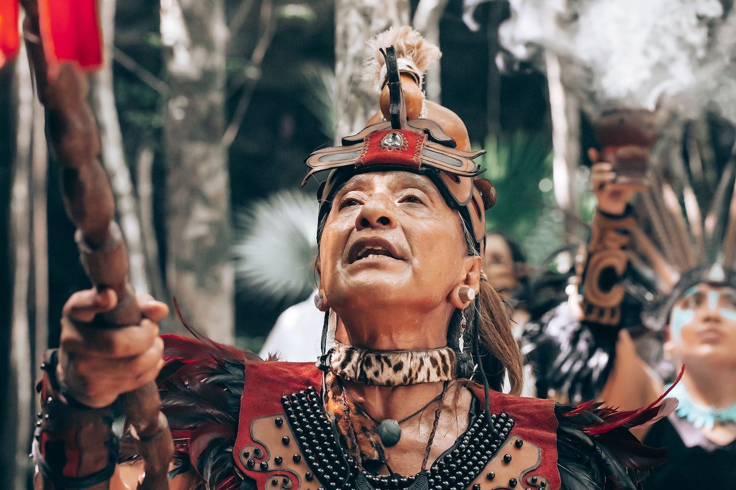 Traditional ceremony performers in cultural dress and headdresses during a ritual.