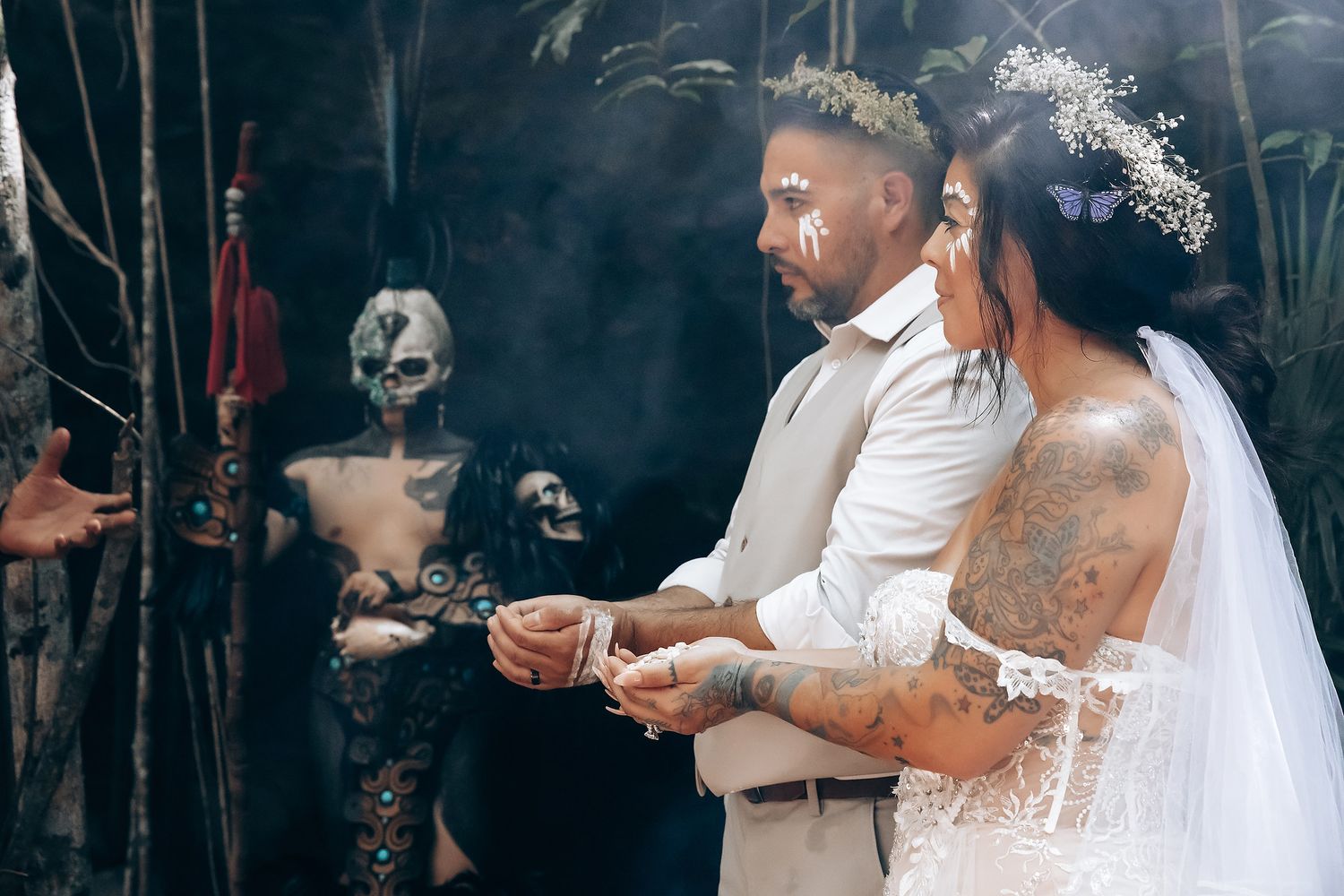 Wedding ceremony participants gather in a mystical forest setting surrounded by smoke and sunbeams.
