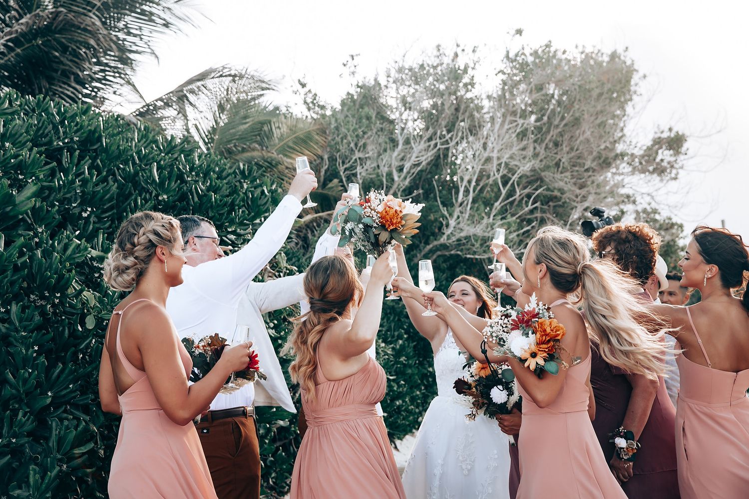Bridesmaids in pink dresses celebrate during outdoor wedding festivities.