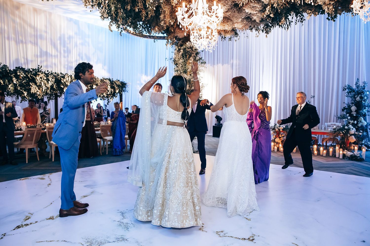 Elegant indoor wedding reception with crystal chandeliers and white floral decorations.
