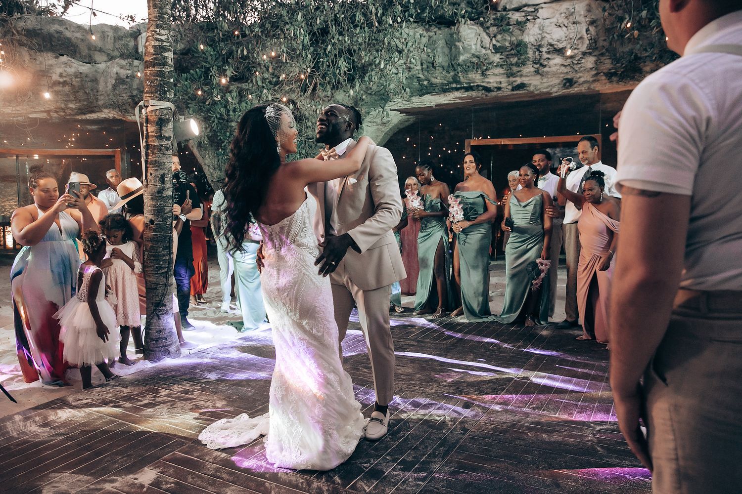 Wedding celebration with guests dancing under string lights in an outdoor venue.
