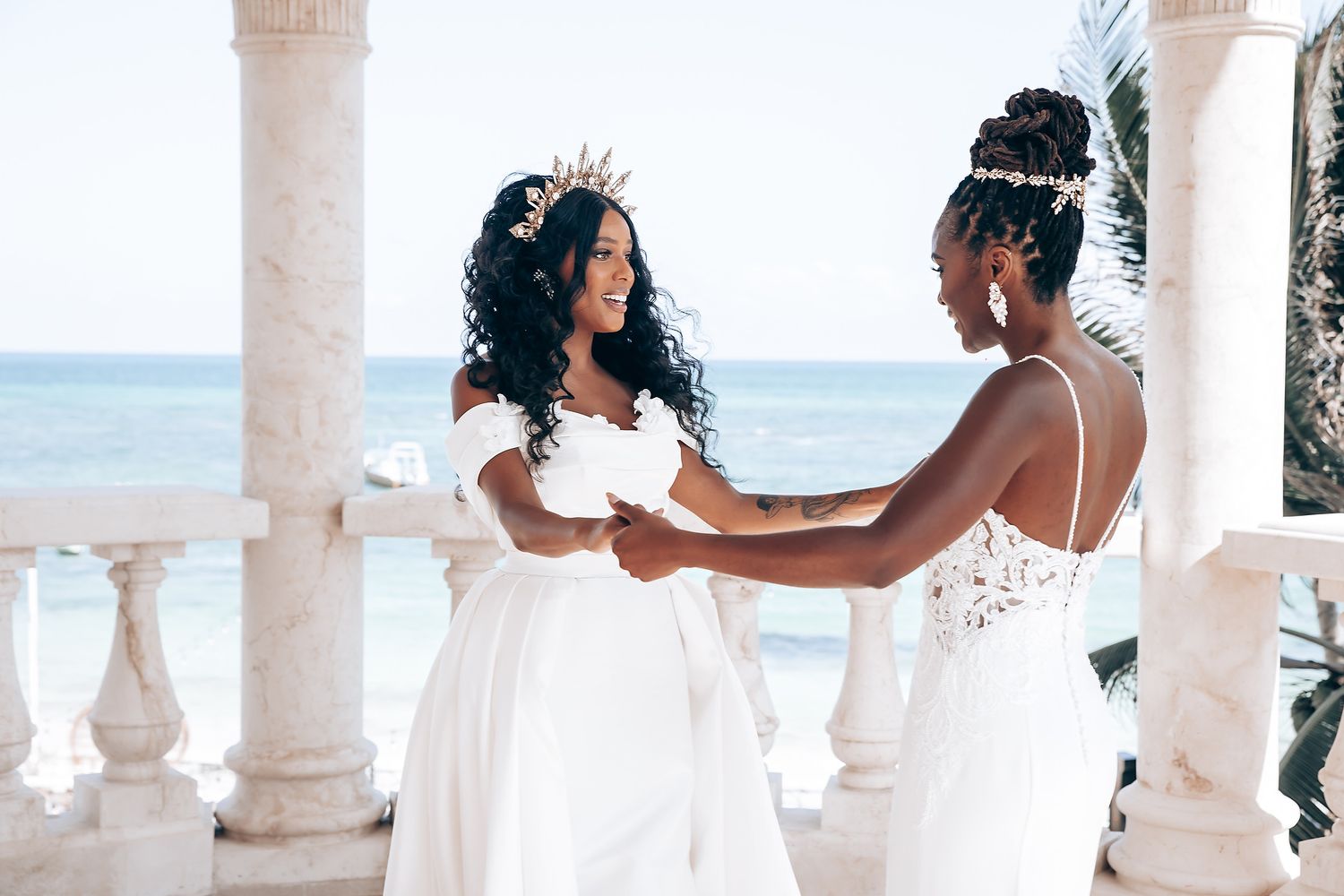 Couple shares an intimate moment under white columns at a beachfront wedding venue with ocean views.