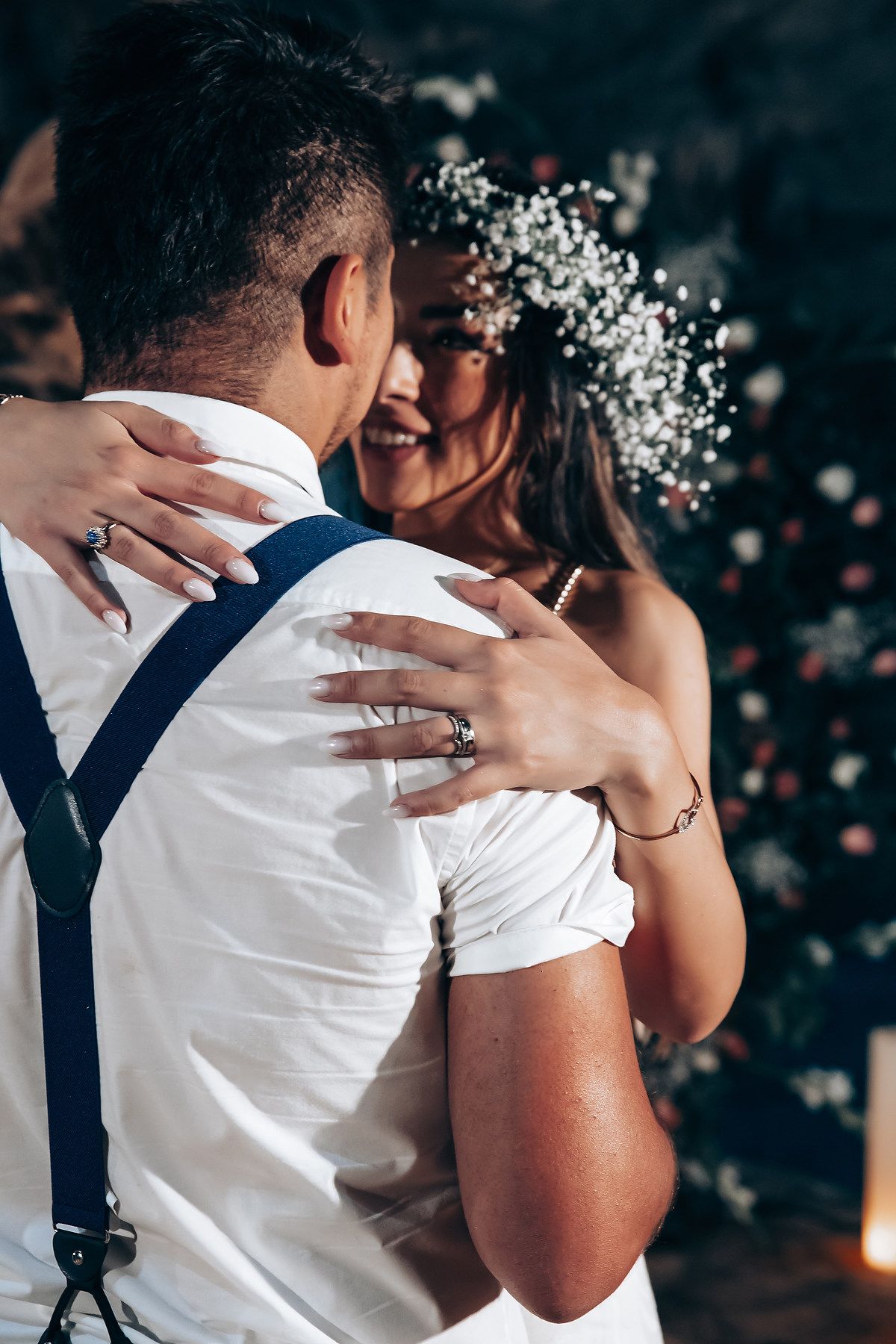 A romantic wedding moment captured in black and white showing an intimate embrace with delicate white flowers in the background.