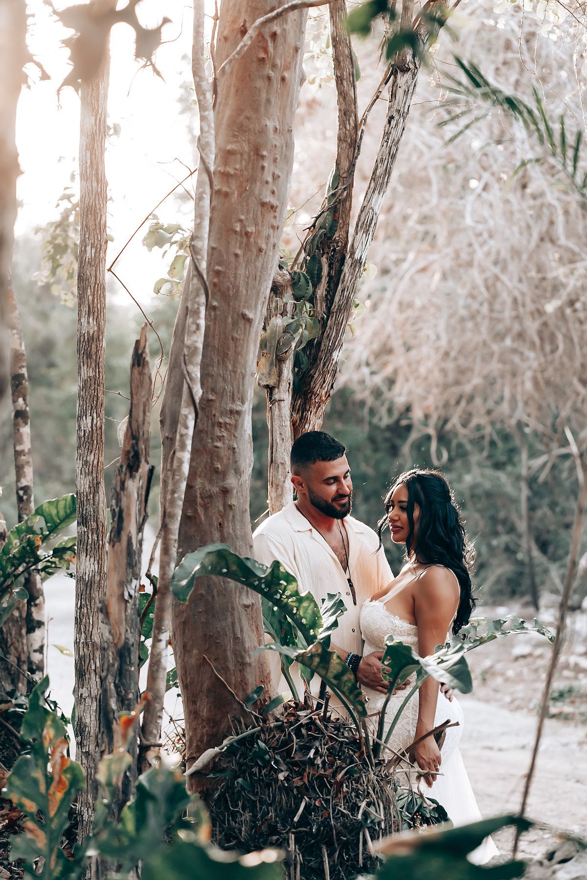Romantic forest wedding photoshoot among tall trees with natural lighting.