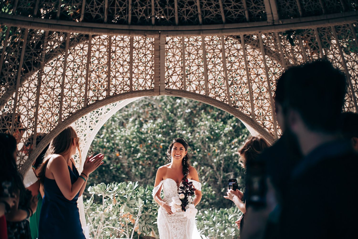 Panoramic view of outdoor wedding ceremony with guests seated under decorative canopy.