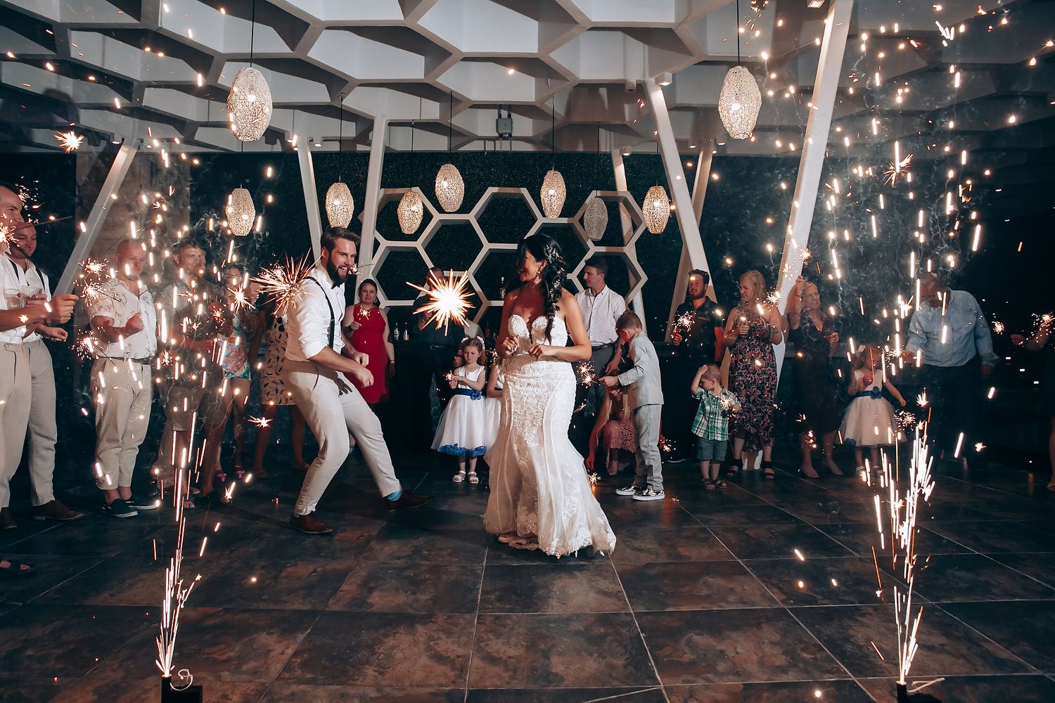 Wedding reception dance floor with sparklers and geometric ceiling decorations creating magical atmosphere.