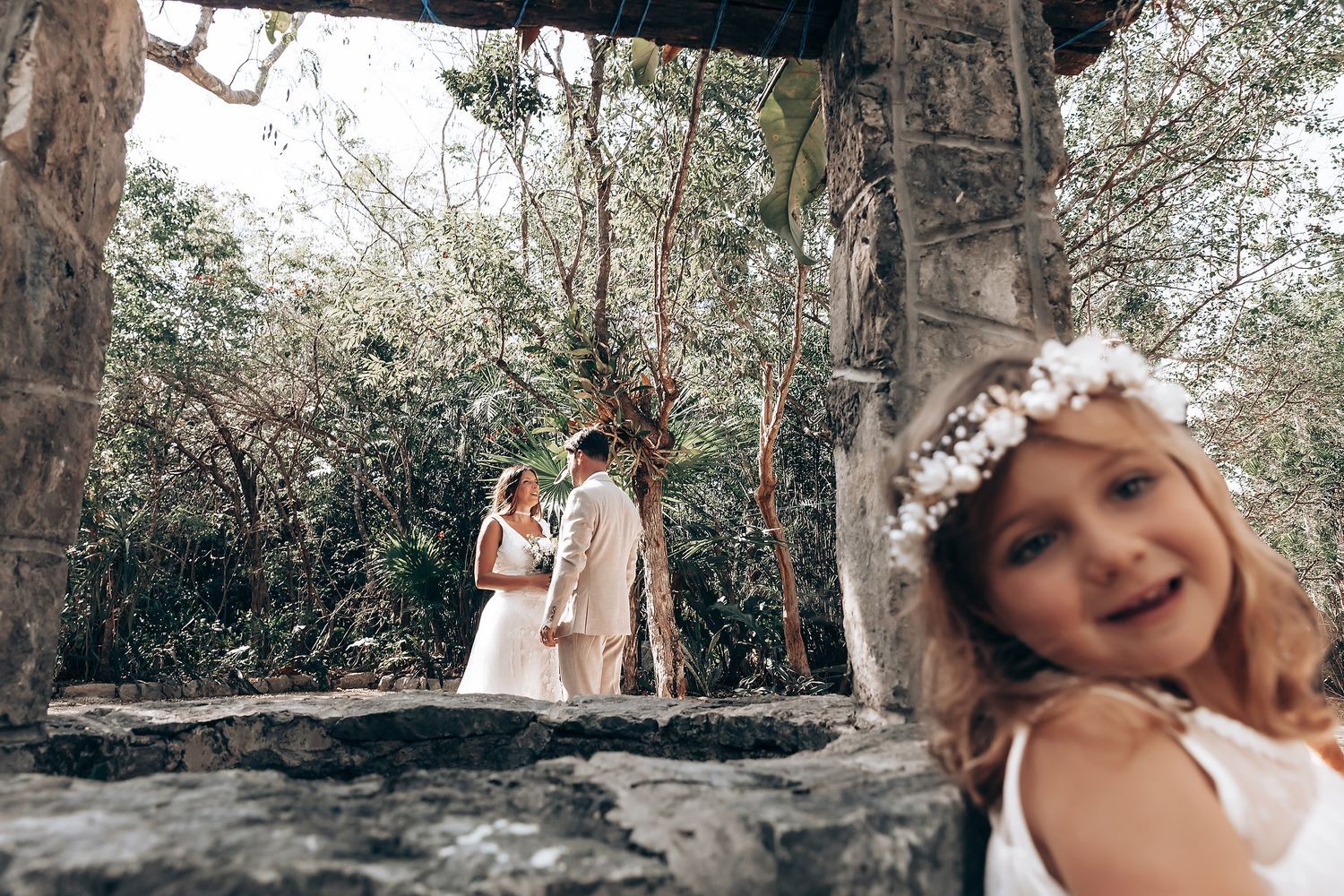 White floral decorations adorn a natural forest setting for an outdoor ceremony.