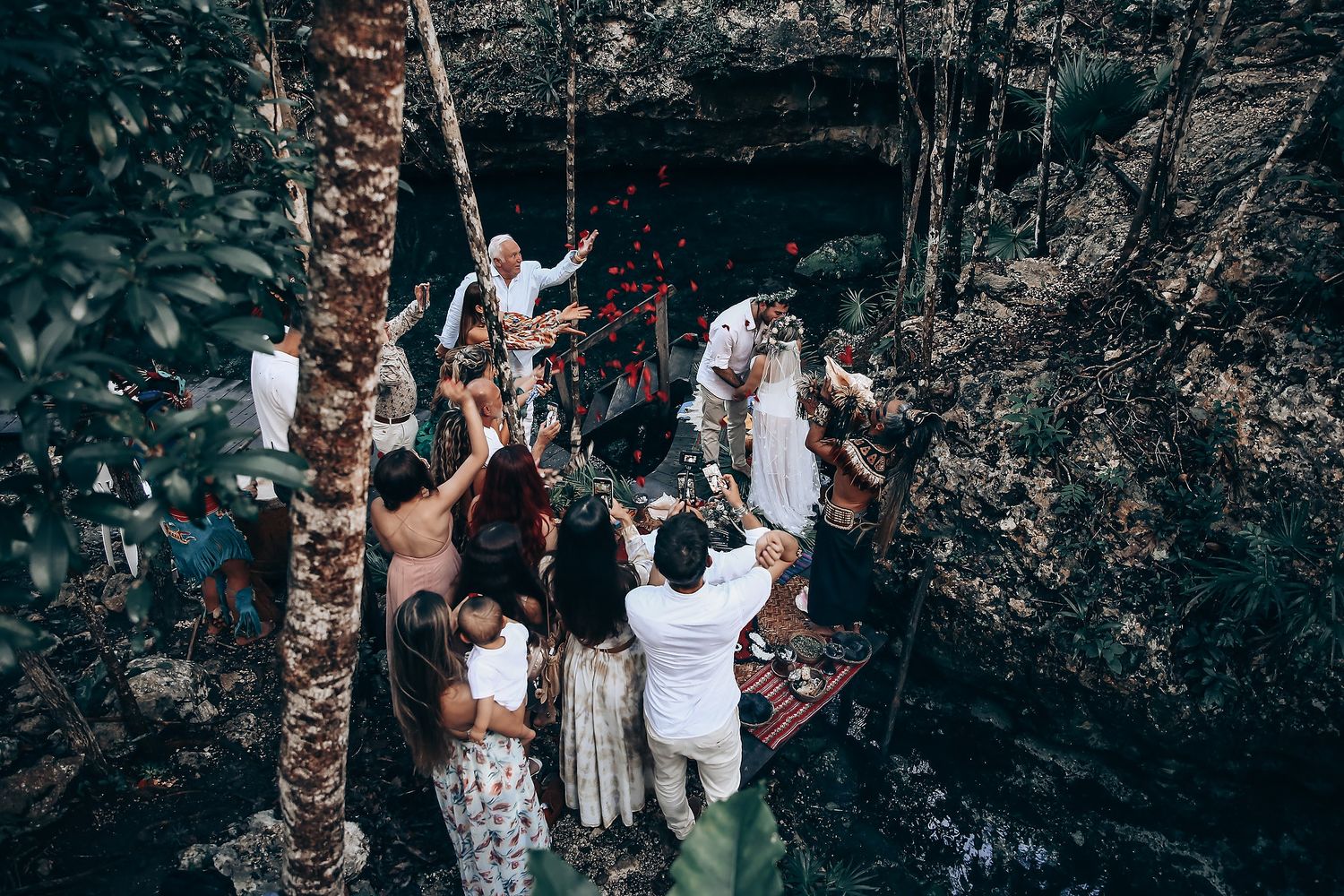 Intimate forest gathering with people in white attire among tall trees.