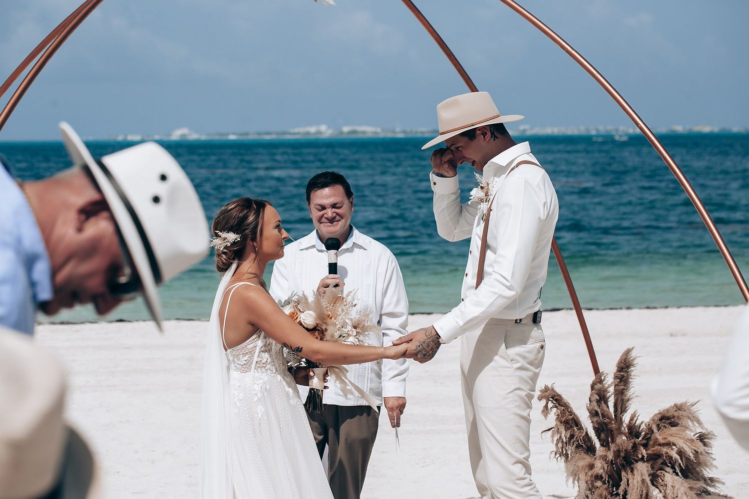 Wedding ceremony arch on a beach with ocean views and tropical decorations.