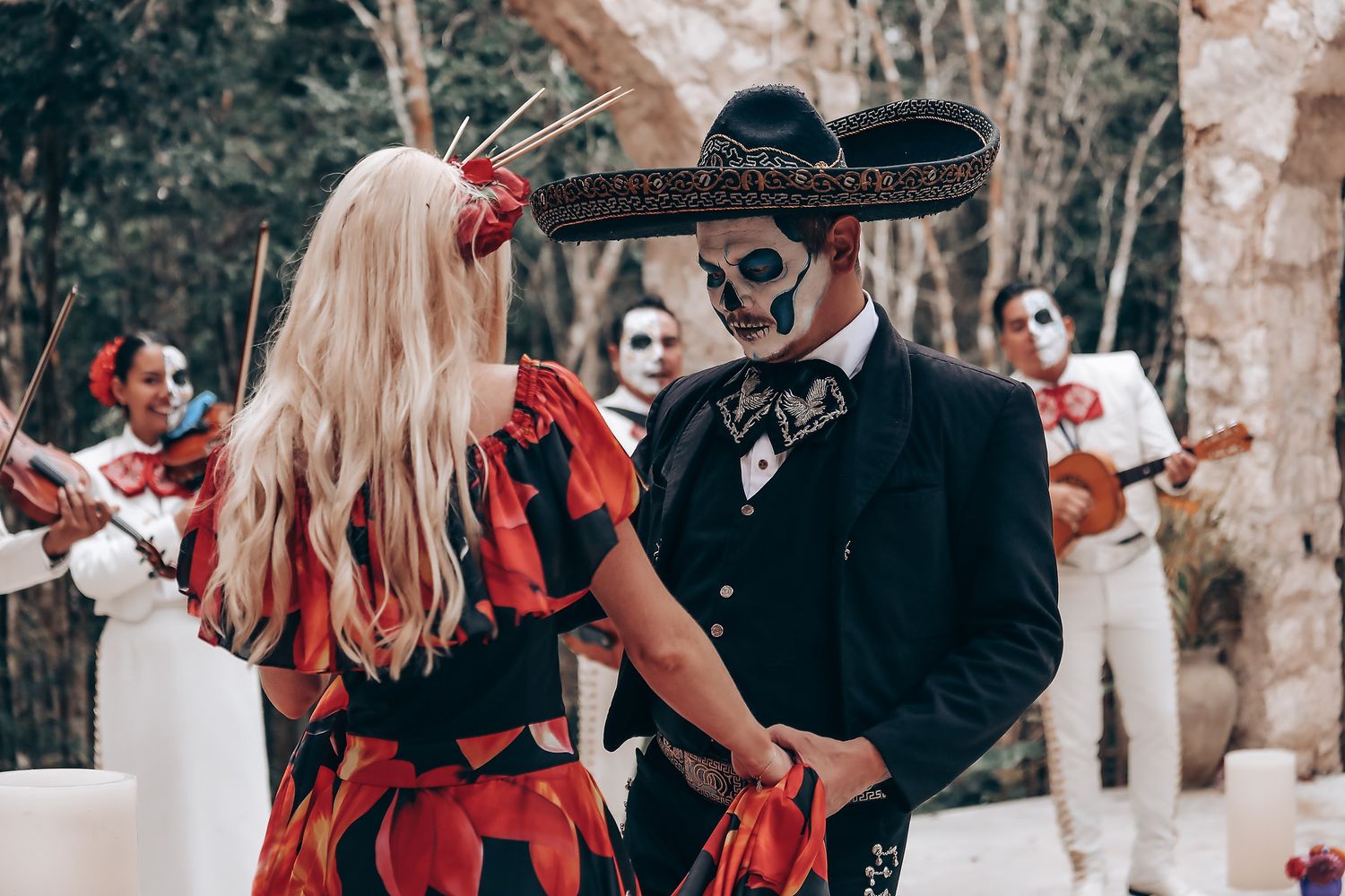 A couple dances while mariachi band performs at outdoor wedding celebration.
