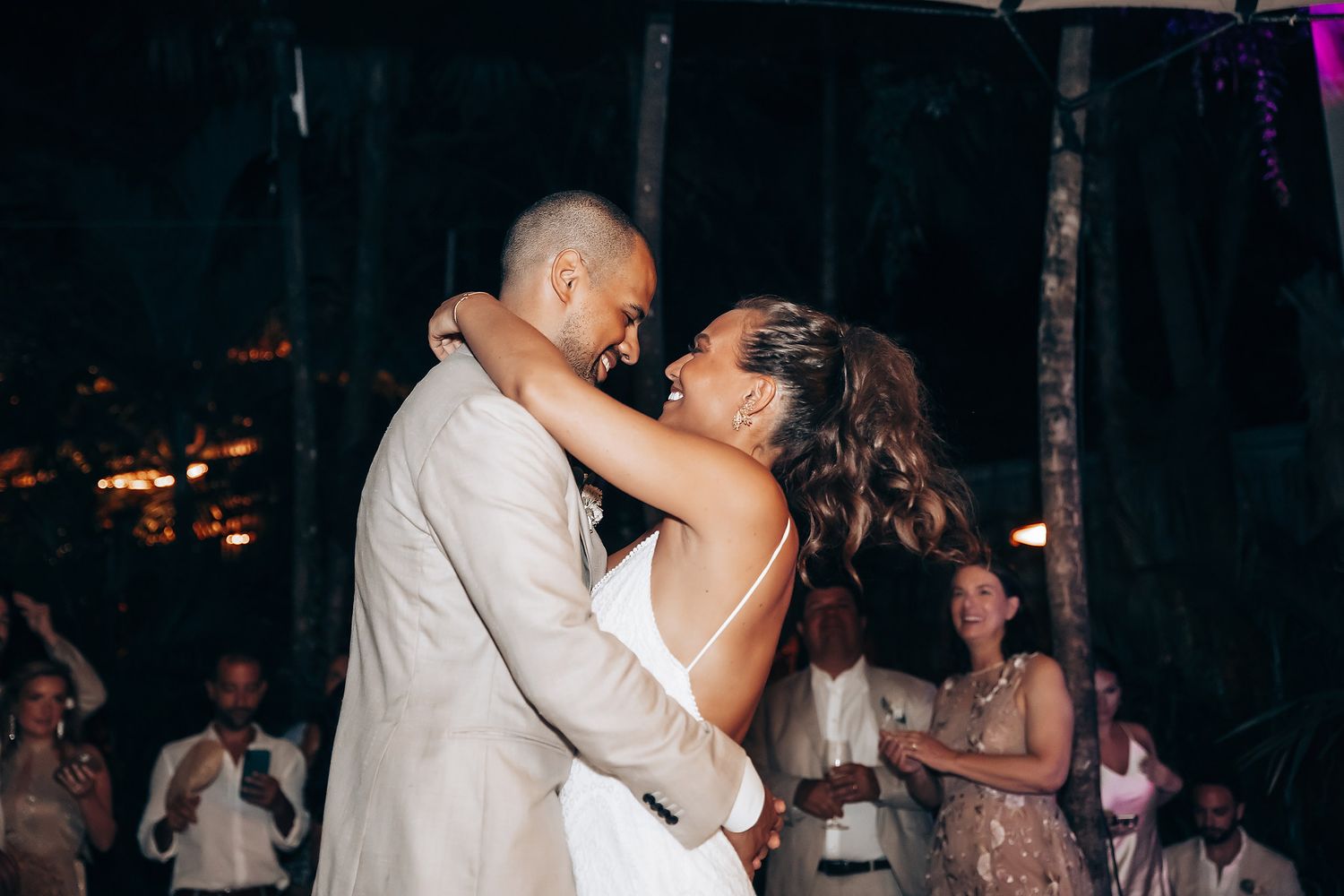 Wedding guests dancing at a nighttime beach reception celebration.