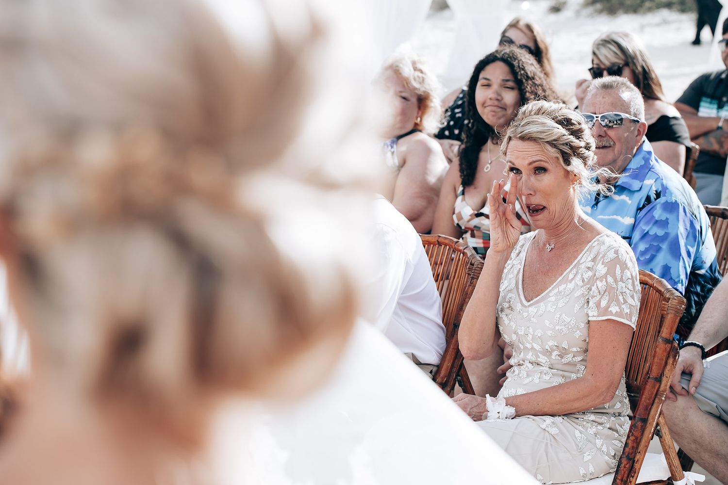 Wedding guests share emotional moments during an outdoor beach ceremony.