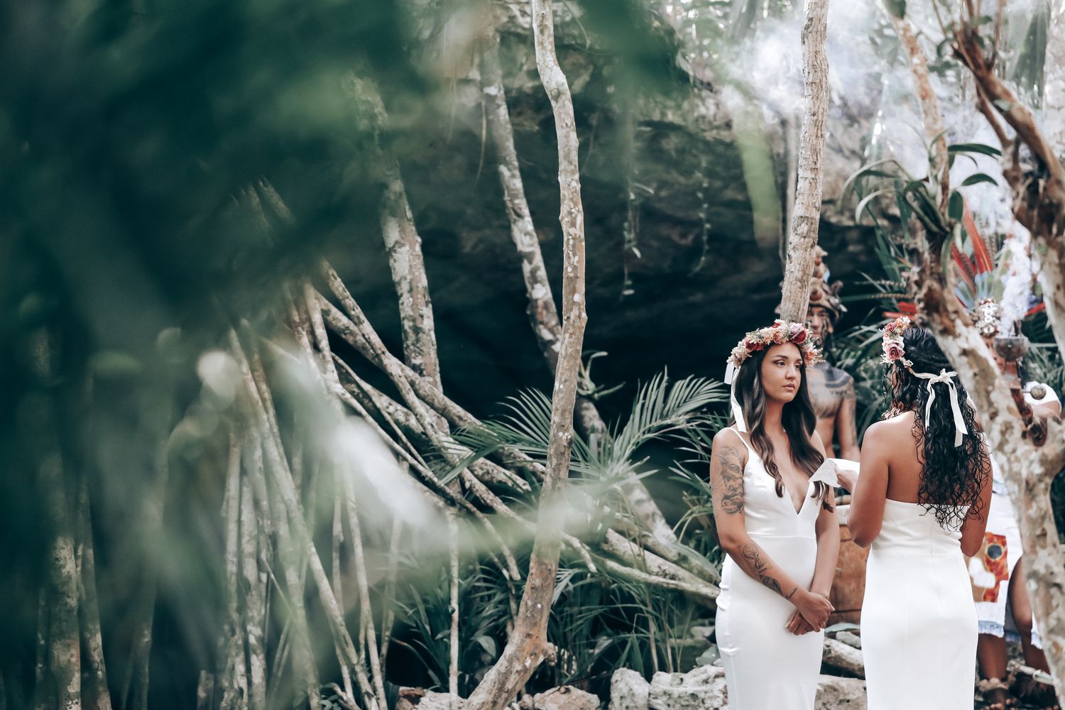 A couple in matching white outfits share an intimate moment among palm trees.