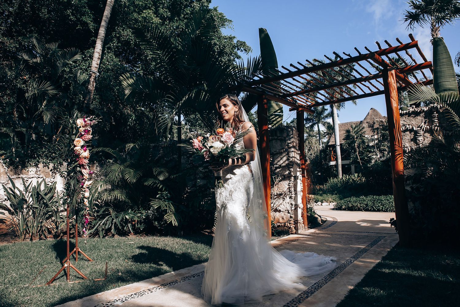 Outdoor wedding ceremony setup with wooden pergola and floral arrangements in a garden setting.