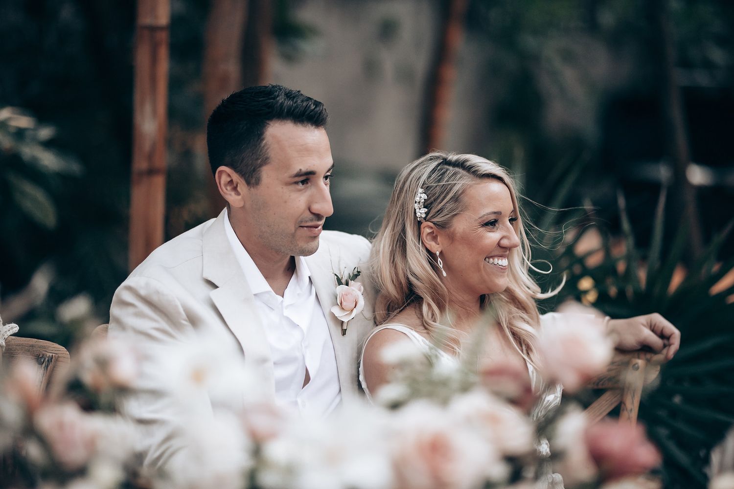 Wedding couple sharing intimate moment among pink floral decorations.