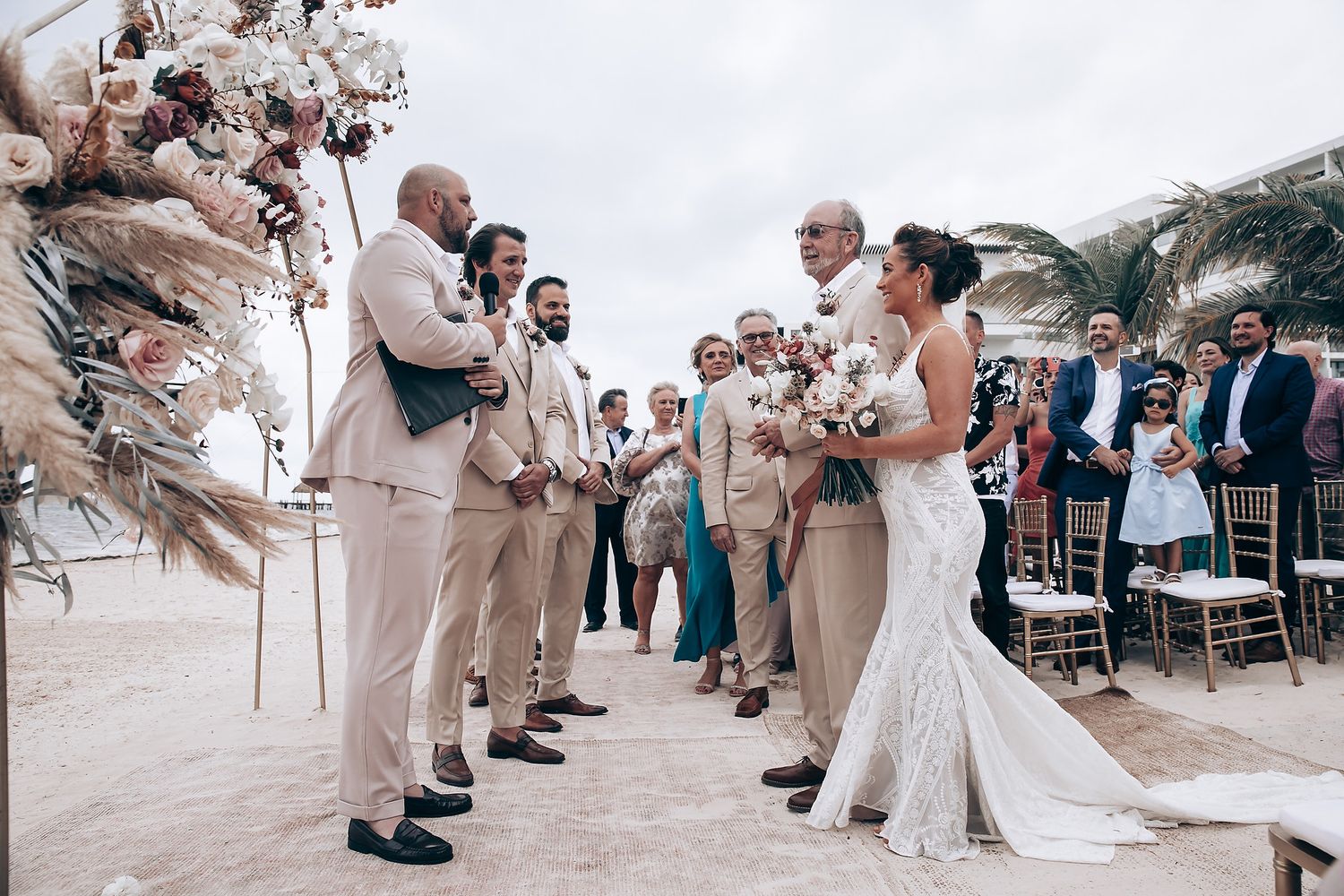 Wedding ceremony on a beachfront terrace with guests gathered around.