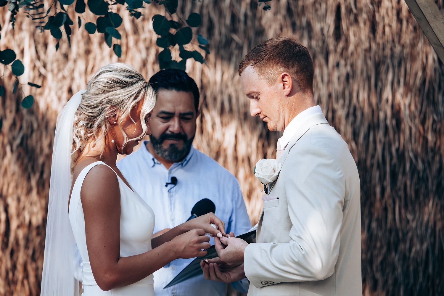 Wedding ceremony exchange of rings under natural outdoor setting.