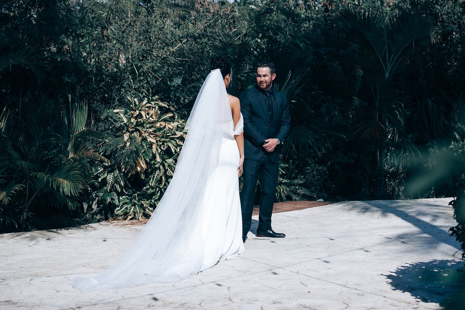 Wedding couple and party members walking through a lush garden pathway.