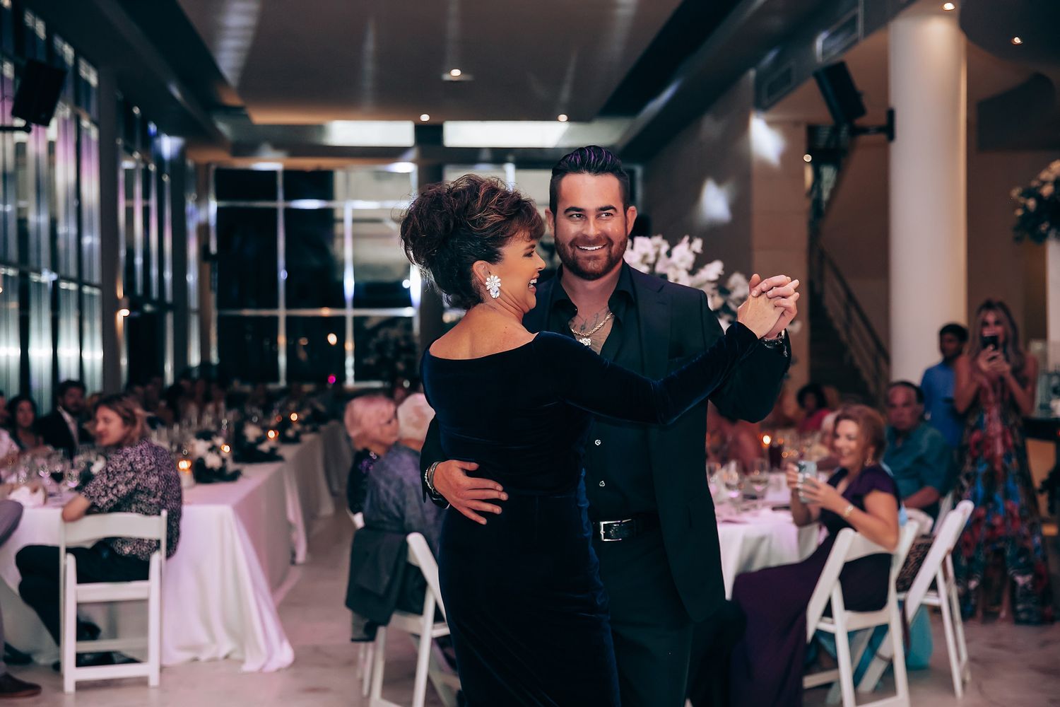 Wedding reception party with guests dancing on an illuminated dance floor.