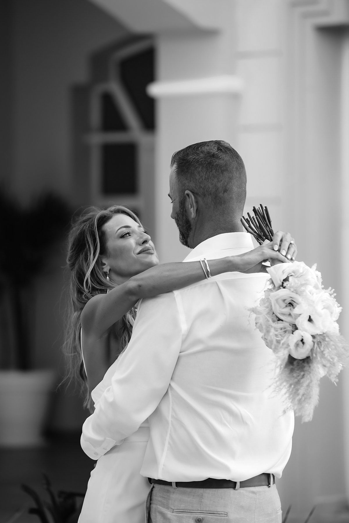 A black and white image showing a couple embracing and dancing at what appears to be a wedding or formal event.