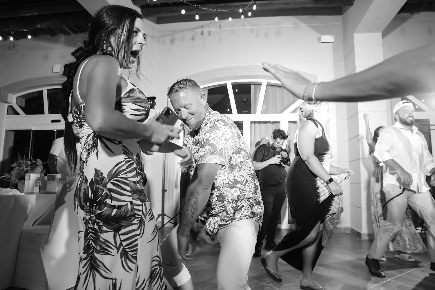 A group of people, including a bride and groom, are dancing and celebrating at a wedding reception.