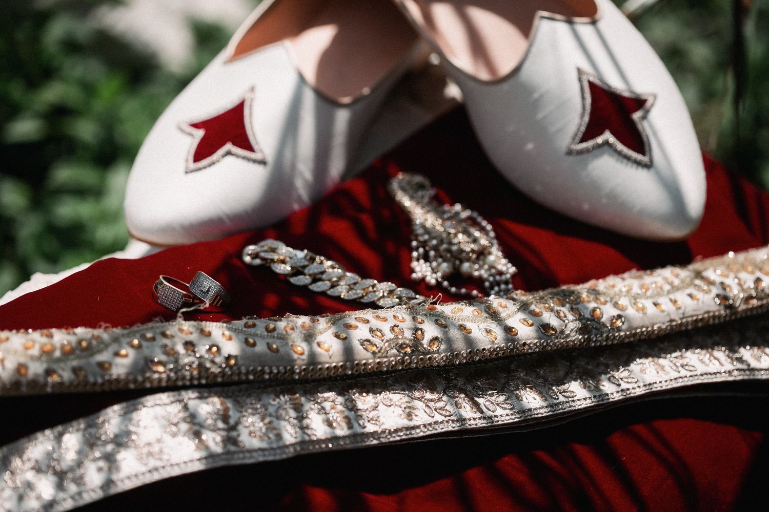 White bridal slippers with red star detail beside sparkling crystal jewelry on a red embroidered fabric.