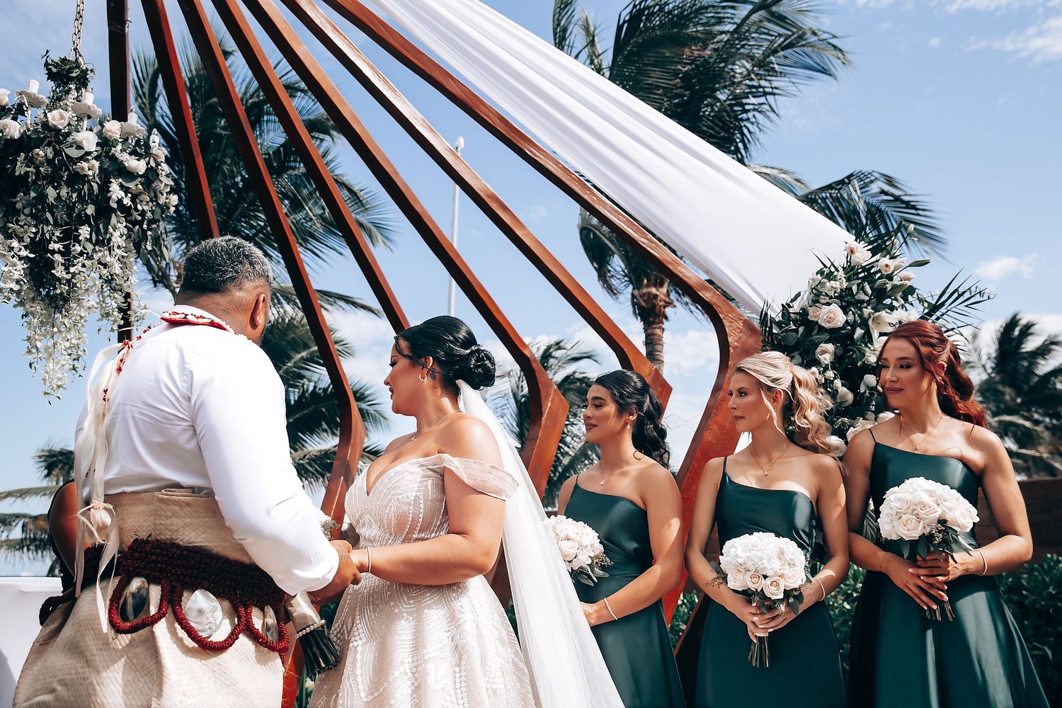 White fabric canopy fluttering in the wind during an outdoor beach wedding ceremony.
