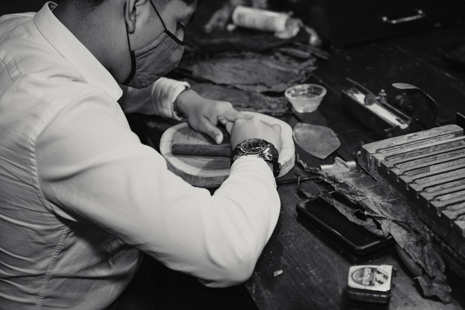 Black and white close-up of a cigar roller crafting cigars at a wedding reception.