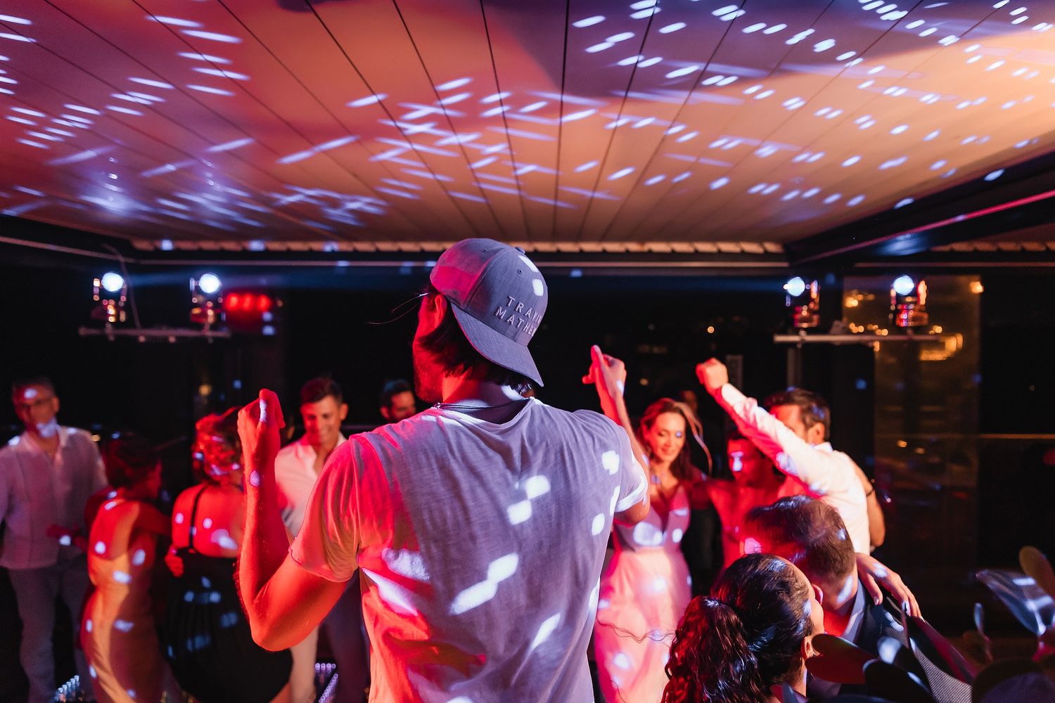 Dance floor illuminated with red and purple lights as guests celebrate at an indoor event.
