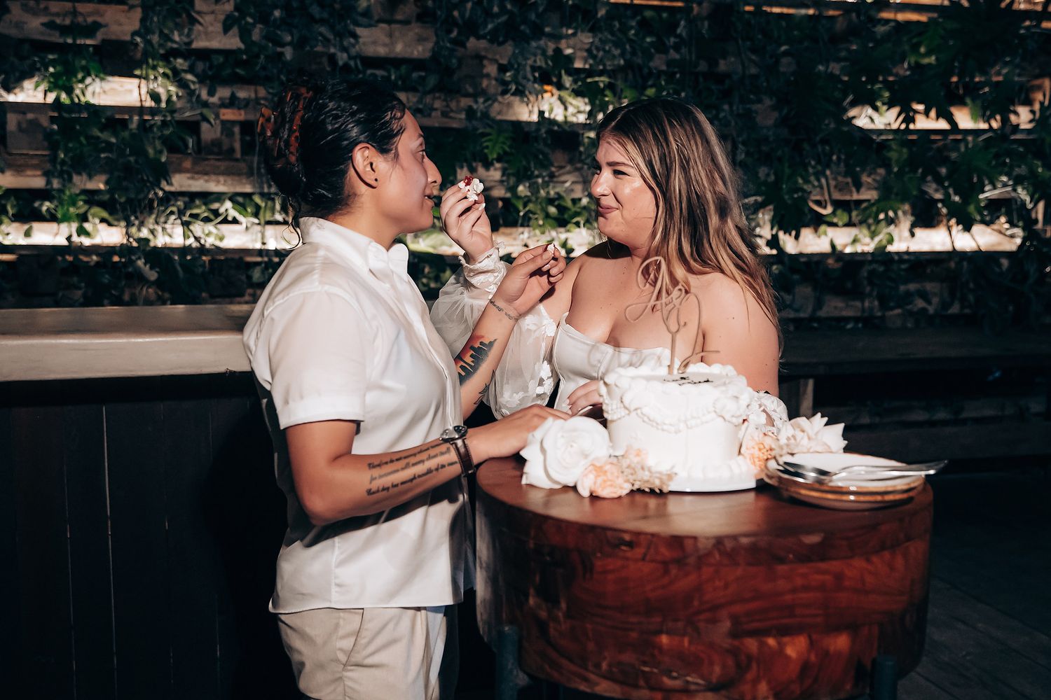 A couple shares an intimate moment in a wine barrel hot tub surrounded by trees at dusk.