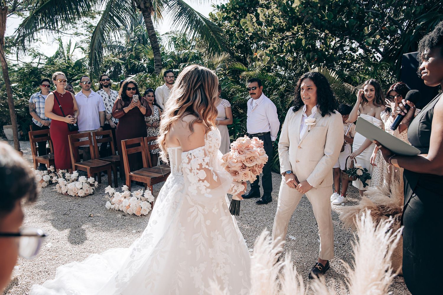 Wedding ceremony setup in a tropical garden with wooden chairs and palm trees in the background.
