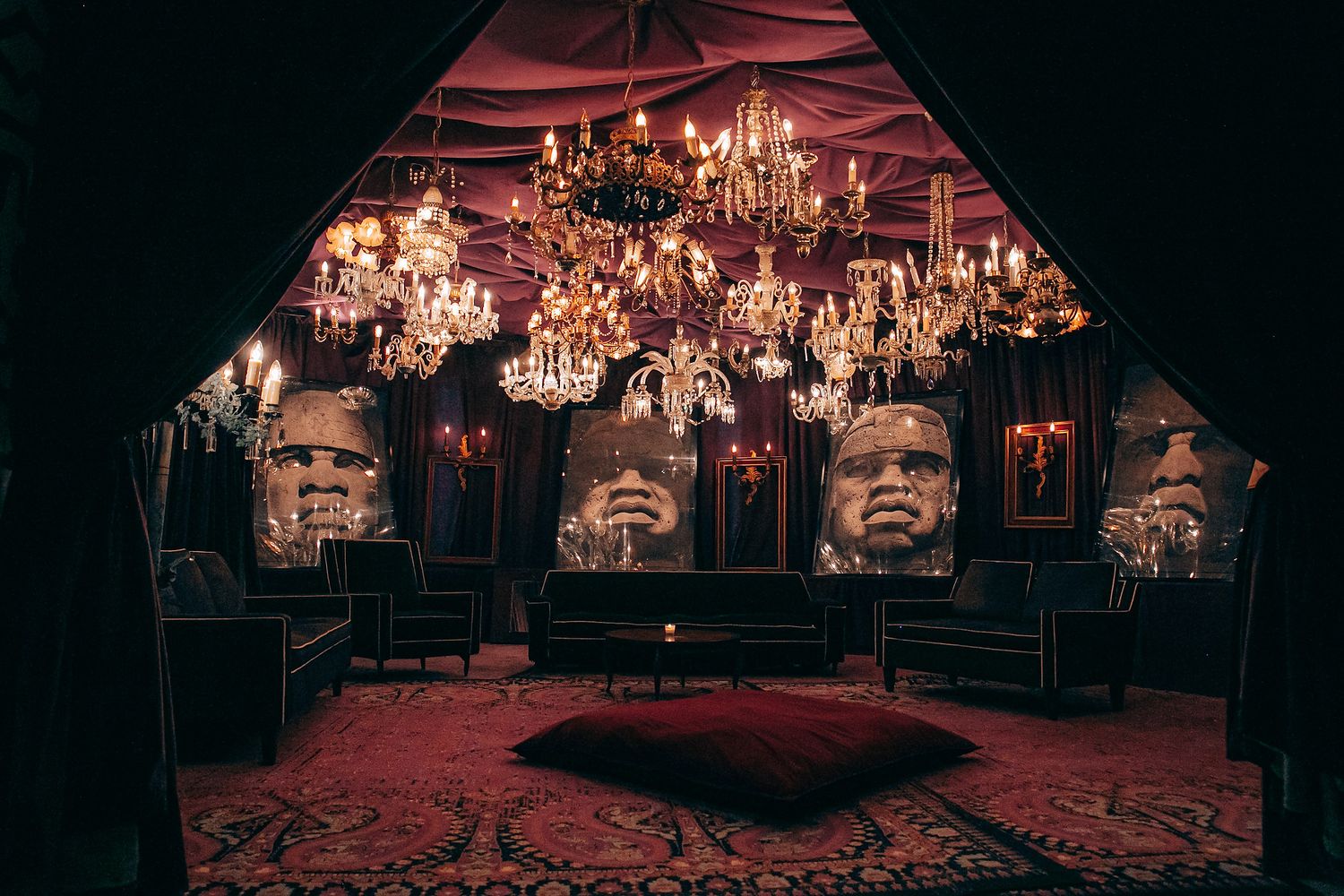 Elegant crystal chandeliers illuminate a dark room with a red glow creating a luxurious and moody atmosphere.