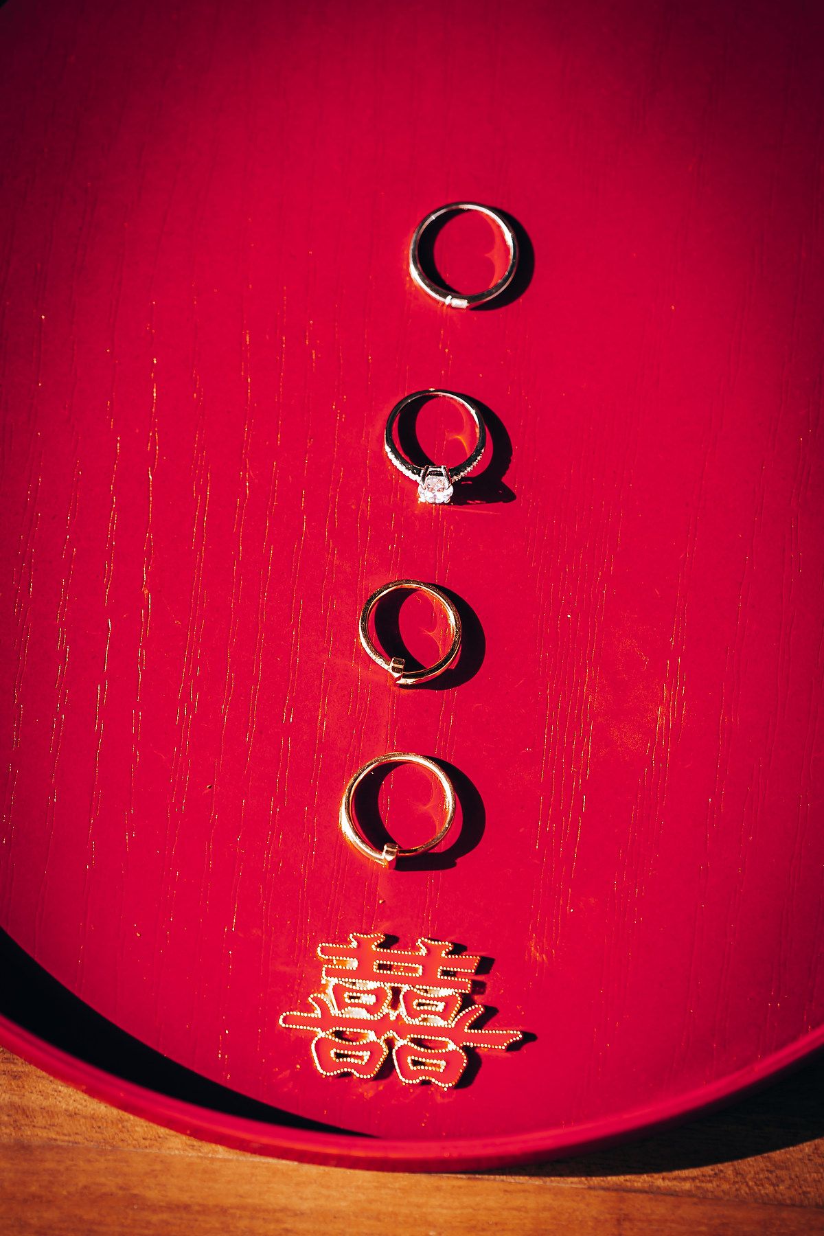 Wedding rings and double happiness symbol displayed on red velvet background.